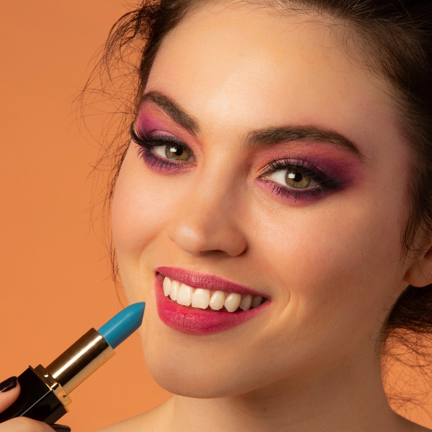 Woman applying blue color-changing lipstick with lip stain finish